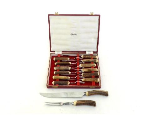 A boxed set of six pairs of steak knives and forks with antler handles retailed by Harrods, together with a carving knife and