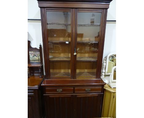 A Victorian library bookcase in mahogany with glazed top section to four shelf interior over two short drawers with cupboards