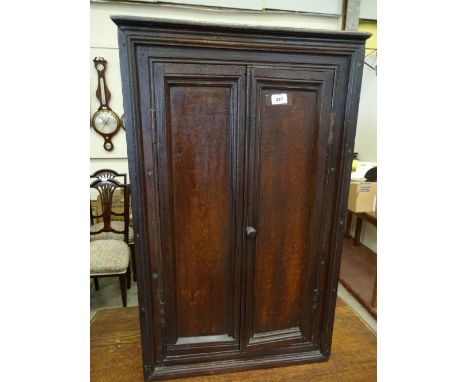 A two door oak wall hanging cupboard with shaped shelf interior, stepped cornice and plinth, 58cm x 30cm x 93cm high