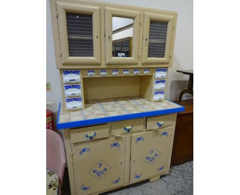A 50's style kitchen unit with glazed cupboard and ceramic drawers over tile work surface with three drawers and double cupbo