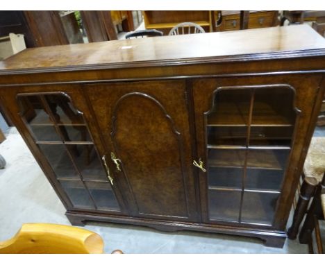 A burr front cabinet with central panel section flanked by glazed cupboards on bracket feet, 123cm x 30cm x 113cm high