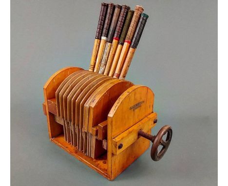 A 1920s-30s oak Slazenger tennis racket press, having adjustable wooden dividers, a cast iron wheel handle, and also includin