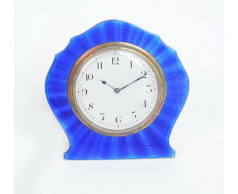 A George V hallmarked silver and blue guilloche enamel decorated travelling clock of shaped form, the circular dial set with 