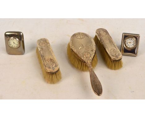 A George V hallmarked silver backed three piece dressing table set comprising a hand brush and pair of coat brushes with engi