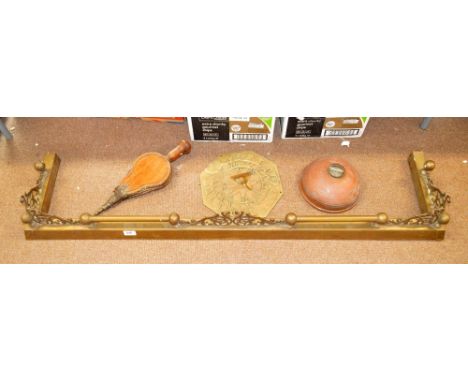 A brass fender with pierced scrolling decoration, width 133.5cm, a pair of wooden studded bellows, an octagonal brass sundial