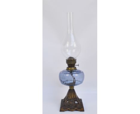 A late Victorian cast iron oil lamp with blue glass reservoir above tapering square floral decorated base, height 53cm includ