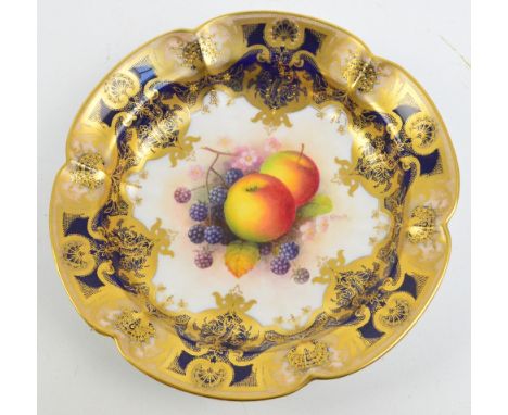 A Royal Worcester bowl with hand painted fruit decorated central panel by Albert Shuck within a blue and gilt heightened bord