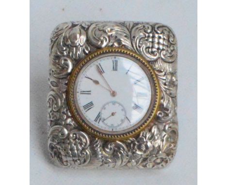 A Victorian hallmarked silver fronted eight day travelling clock of rounded rectangular form embossed with foliate scrolls, t