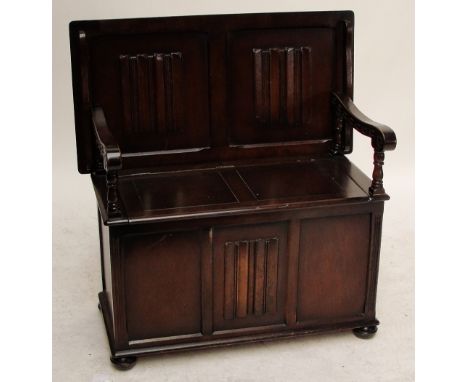 An oak monk's bench with linen fold decorated front panel, width 101.5cm.
