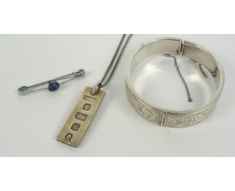 A sterling silver snap bangle engraved with foliate scrolls, an Elizabeth II hallmarked silver ingot pendant on white metal c