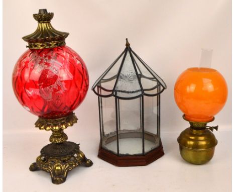 A decorative table lamp modelled as an oil lamp with large globular cranberry glass reservoir above ornamental cast brass bas