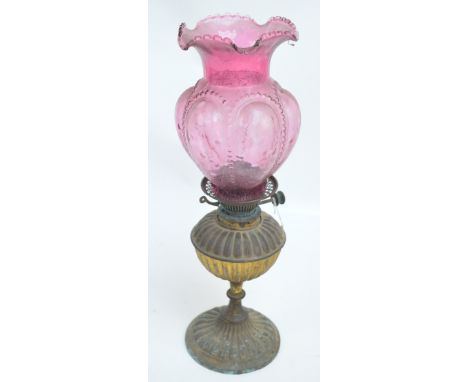 A Victorian oil lamp with brass gadrooned reservoir above similarly decorated spreading circular foot with ruby tulip bead de
