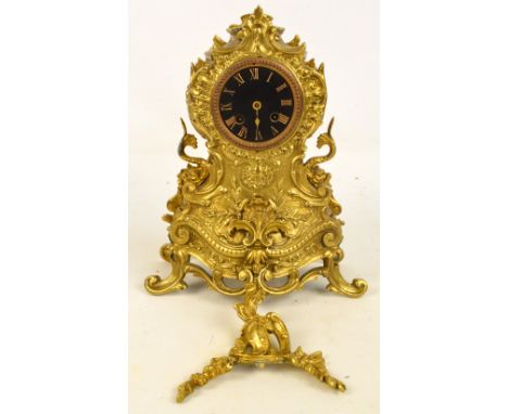 A decorative French brass mantel clock with Roman numerals to the black painted dial with eight day movement and scrolling ca
