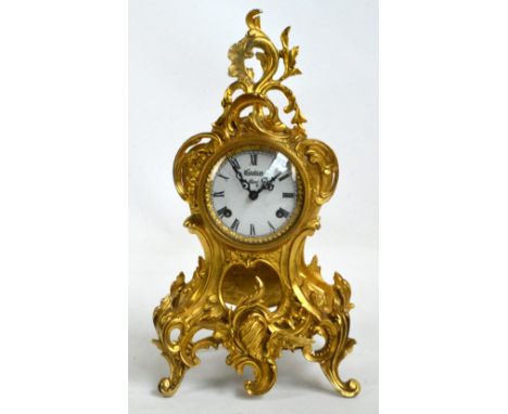 A 1950s decorative gilt metal mantel clock, the scrolling case centred with a white enamel dial set with Roman numerals inscr