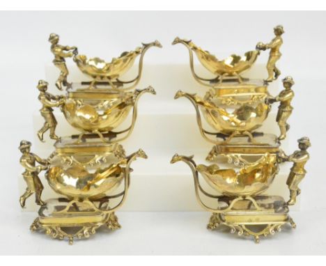A cased set of six early to mid 19th century German silver gilt sleigh salts, each modelled with a figure standing behind a s