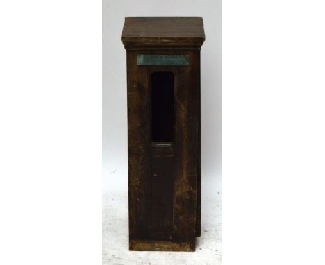 A wooden freestanding car park ticket dispensing machine with a plaque stating "Tickets" above an aperture and a printing blo
