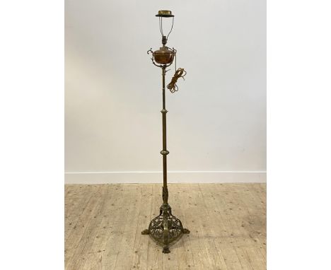 An late Victorian brass and copper lamp standard, on hairy paw cast supports, converted from oil, the reservoir with presenta