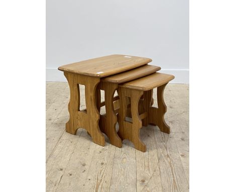 Ercol, a blonde elm nest of three tables, each with a shaped rectangular top raised on pierced panel end supports, H42cm, W58