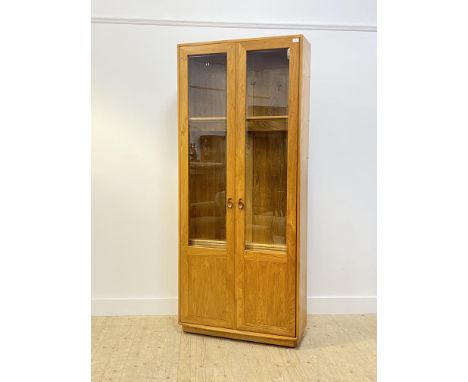 Ercol, a blonde elm display cabinet bookcase, two glazed doors enclosing an illuminated interior fitted with fixed and adjust