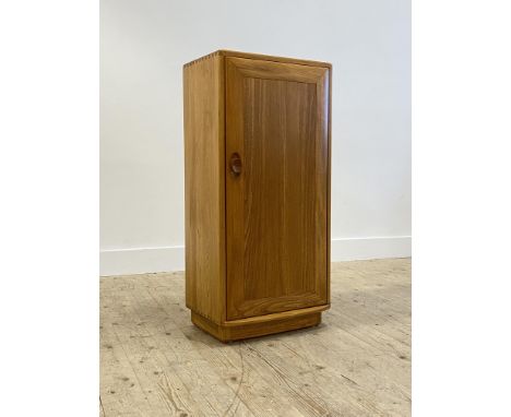 Ercol, An elm cabinet, late 20th century, the single door enclosing two adjustable shelves, raised on a recessed pedestal foo