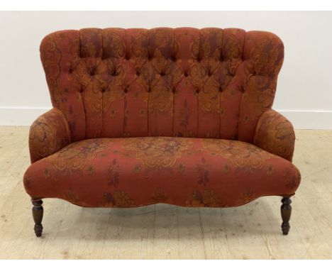 A Victorian style two seat sofa, possibly Derwent, upholstered in a deep red floral and buttoned fabric, raised on turned fro