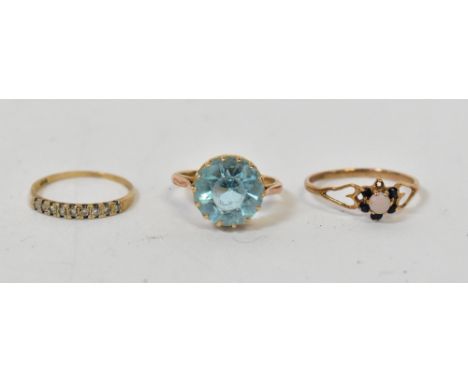 Three gold rings comprising an example with large claw set pale blue stone, size K, marks rubbed, a 9ct gold ring set with sm