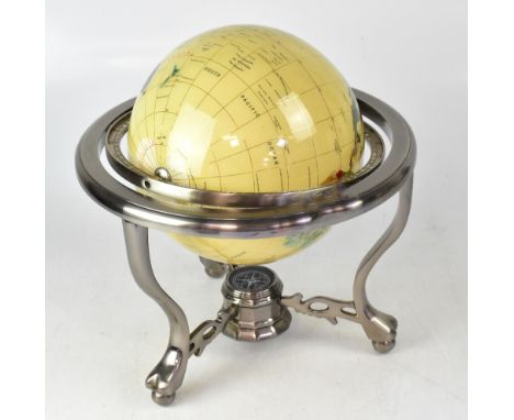 A small hardstone globe raised on a white base metal gimbal, united by a stretcher with a compass, 33 x 32cm.