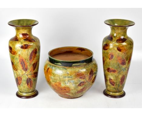 ROYAL DOULTON; a large pair of baluster vases decorated with leaves in Autumnal colours, raised on spreading circular bases, 