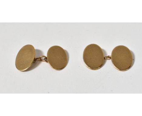 A pair of 1930s 9ct gold oval cufflinks, with engine turned decoration, united with 9ct gold chain, length approx 1.9cm, comb