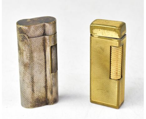 DUNHILL; two lighters comprising a yellow metal engine turned example and a similar silvered example, length 6.6cm (2). CONDI