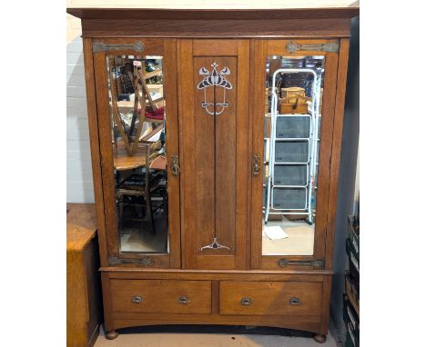 An Edwardian oak double wardrobe with inlaid Arts and Crafts motifs.