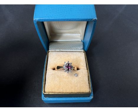 A yellow metal ring set with a central ruby surrounded by 10 diamonds, 2.7gm.