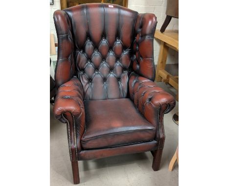 A deep button wingback library armchair in red leather