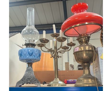 A Victorian cast iron and blue glass oil lamp; a reproduction brass oil lamp and a 7-light brass table candelabra.