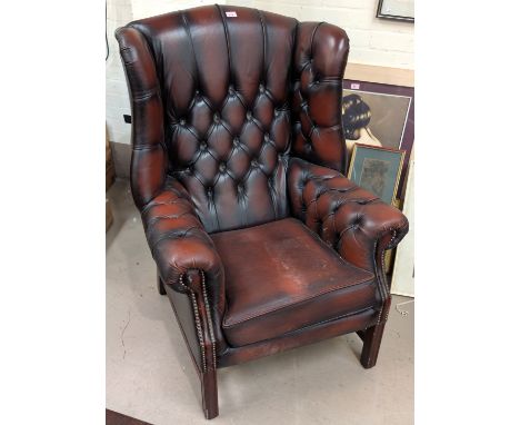 A deep button wingback library armchair in red leather
