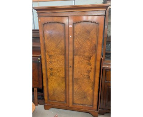 A period-style walnut-effect two-door wardrobe and bed head.