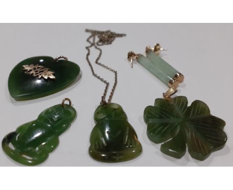 A small group of carved jade and green stone pendants and earrings having gold decoration, pendant loops and mounts together 