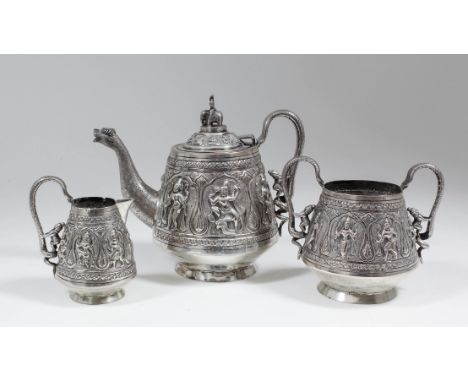 A Siamese silvery metal three piece tea service, the tapered bodies embossed and chased with dancing deities, comprising tea 