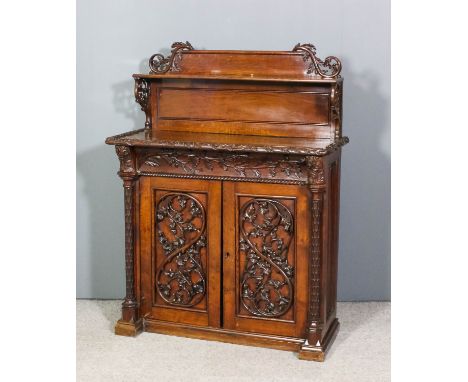 A Victorian oak chiffonier of Gothic design with applied and relief leaf carving throughout, the back with open shelf, on scr