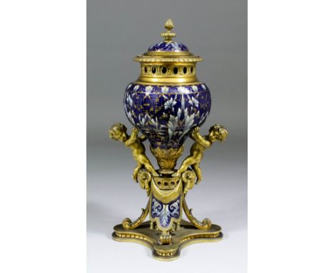 A late 19th Century Continental gilt brass and champleve enamel pot-pourri with cast cherub supporters on a raised quadrupite