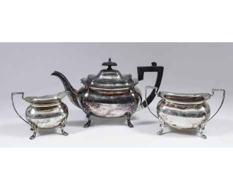 A George V silver rectangular three piece tea service with shaped rims, angular handles and on scroll feet, comprising - teap