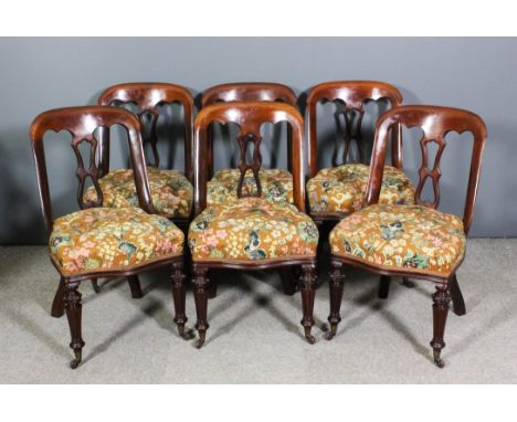A set of six Victorian mahogany dining chair with tub shaped backs and pierced splats, the seats upholstered in tapestry and 