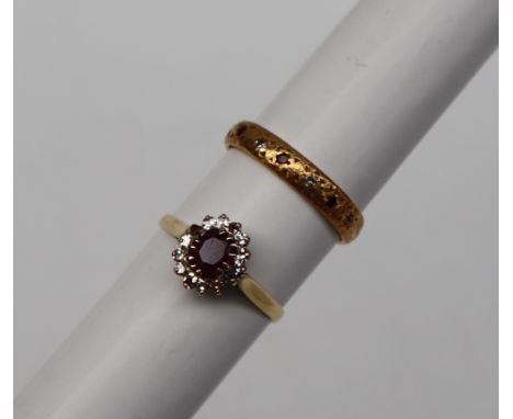 An 18ct yellow gold ruby and diamond cluster ring, set with a  central oval faceted ruby surrounded by round brilliant cut di