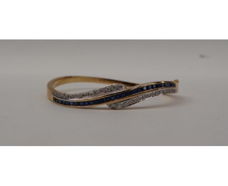 An 18ct gold sapphire and diamond hinged bangle, set with a central row of princess cut diamonds and two rows of round brilli