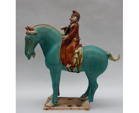 A Tang Dynasty style pottery statuette of a horse mounted with a bearded musician playing a string instrument , in brown, tur
