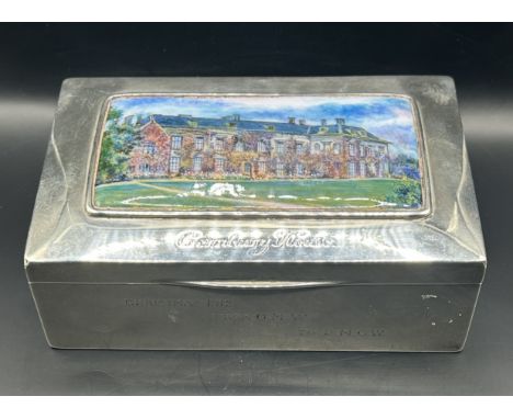 A George V silver table top cigar box, the cover applied an enamel panel of Cornbury House, inscribed, William Hassler, Birmi