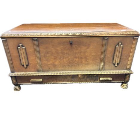Art Deco chest, the lift-up top, above carved moulded decoration to the front panel and lower drawer, raised on turned feet [