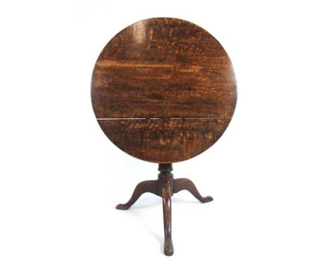 An 18th century oak tilt top tripod table, the circular top on a turned column and three splay legs, h. 67 cm, dia. 76 cm CON