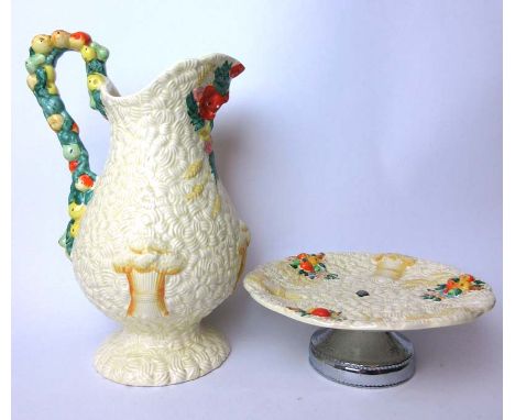 A Clarice Cliff Celtic Harvest jug and footed bowl decorated with embossed wheat sheaf and fruit decoration on a cream ground