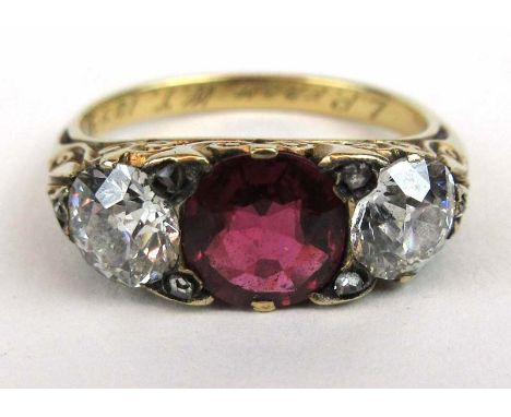 A late 19th century yellow metal ruby and diamond ring, the central ruby (approximately 1ct) flanked by two approximately 0.5